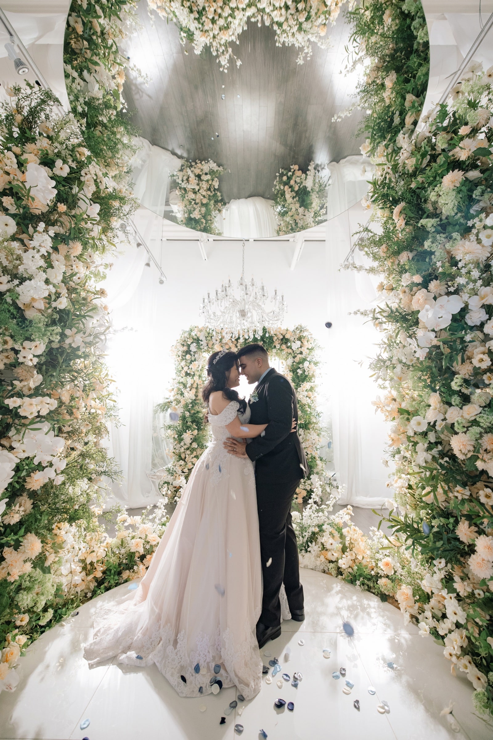 The couple amid a lush floral arch at an intimate micro wedding
