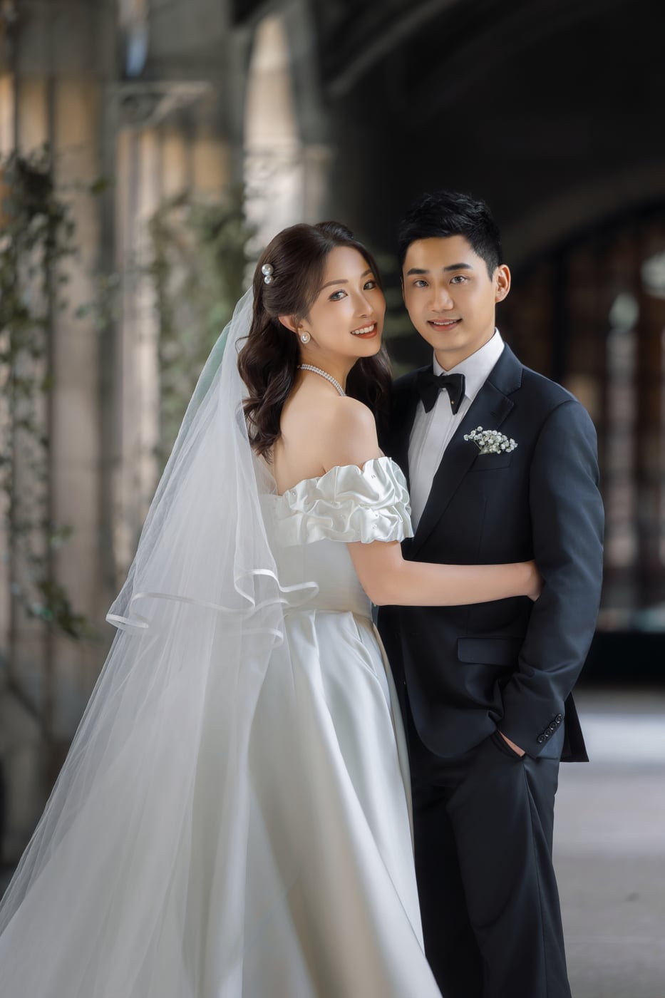 Pre-wedding portrait at Knox College — the couple arm in arm in the stone cloister, the bride in a veil