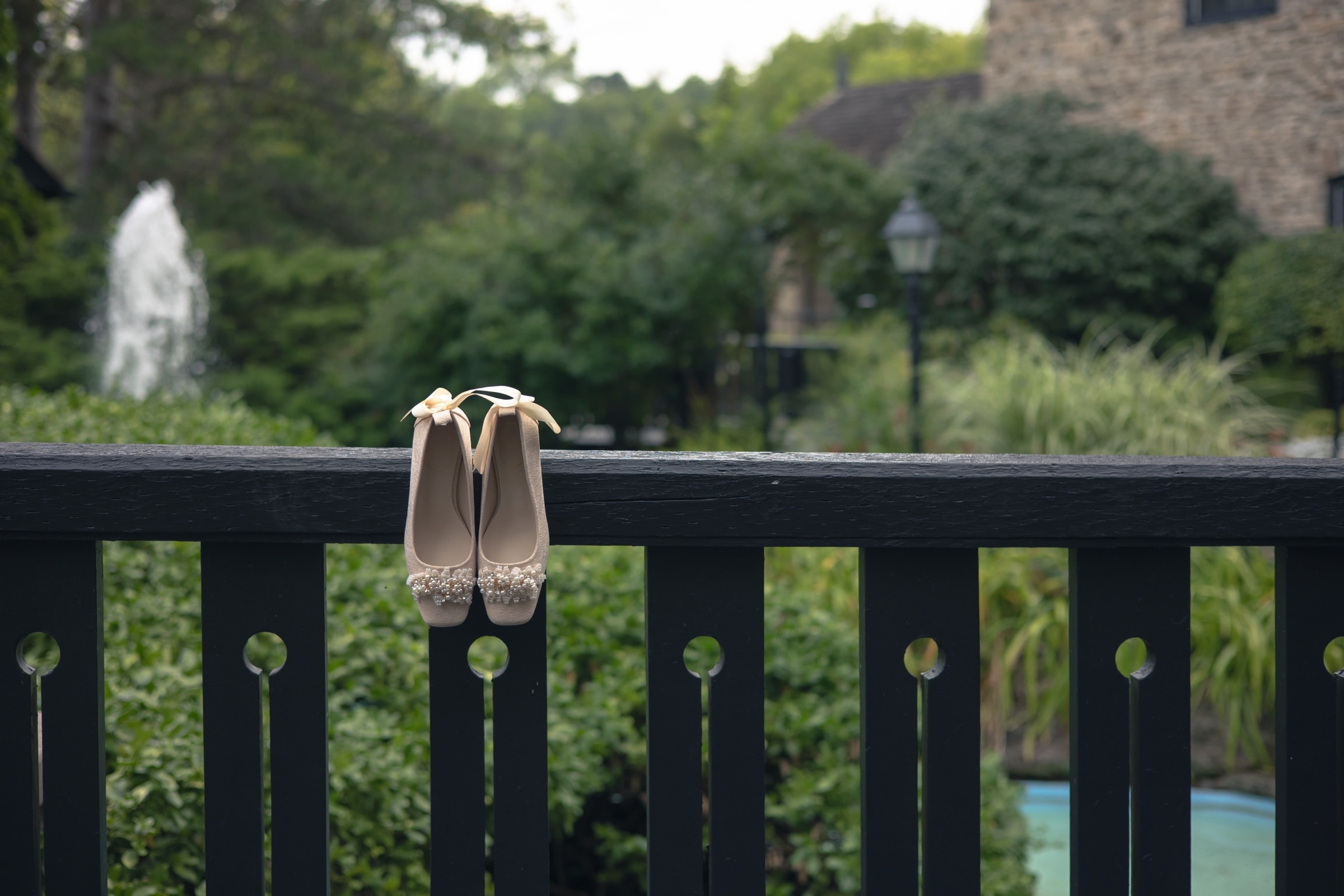 The bride's ivory wedding shoes resting on a wooden railing