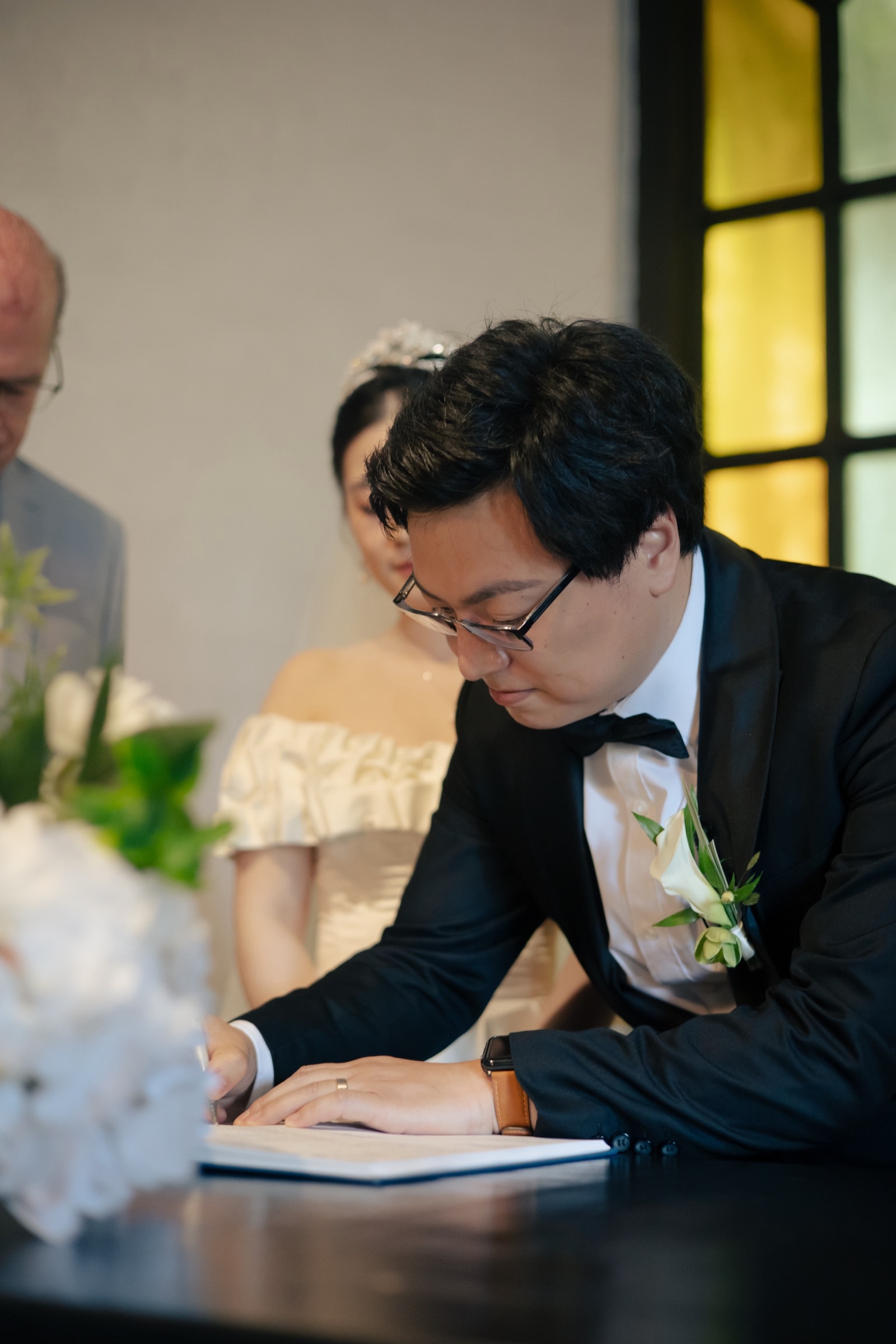 The couple before the officiant beneath the stained-glass windows