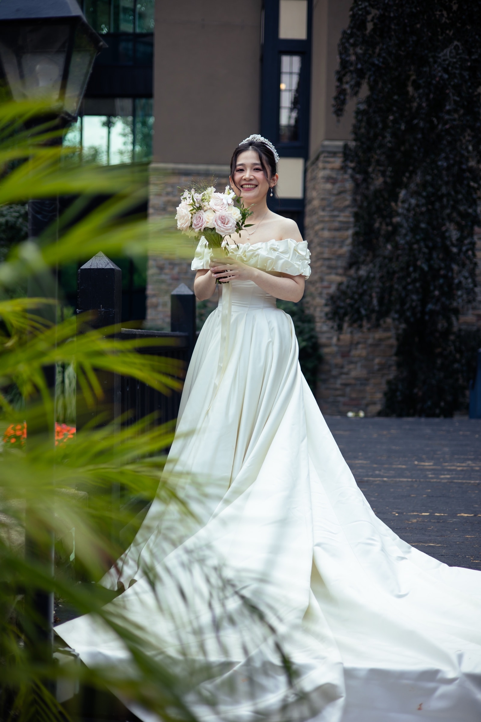 The bride with her bouquet beside a garden window
