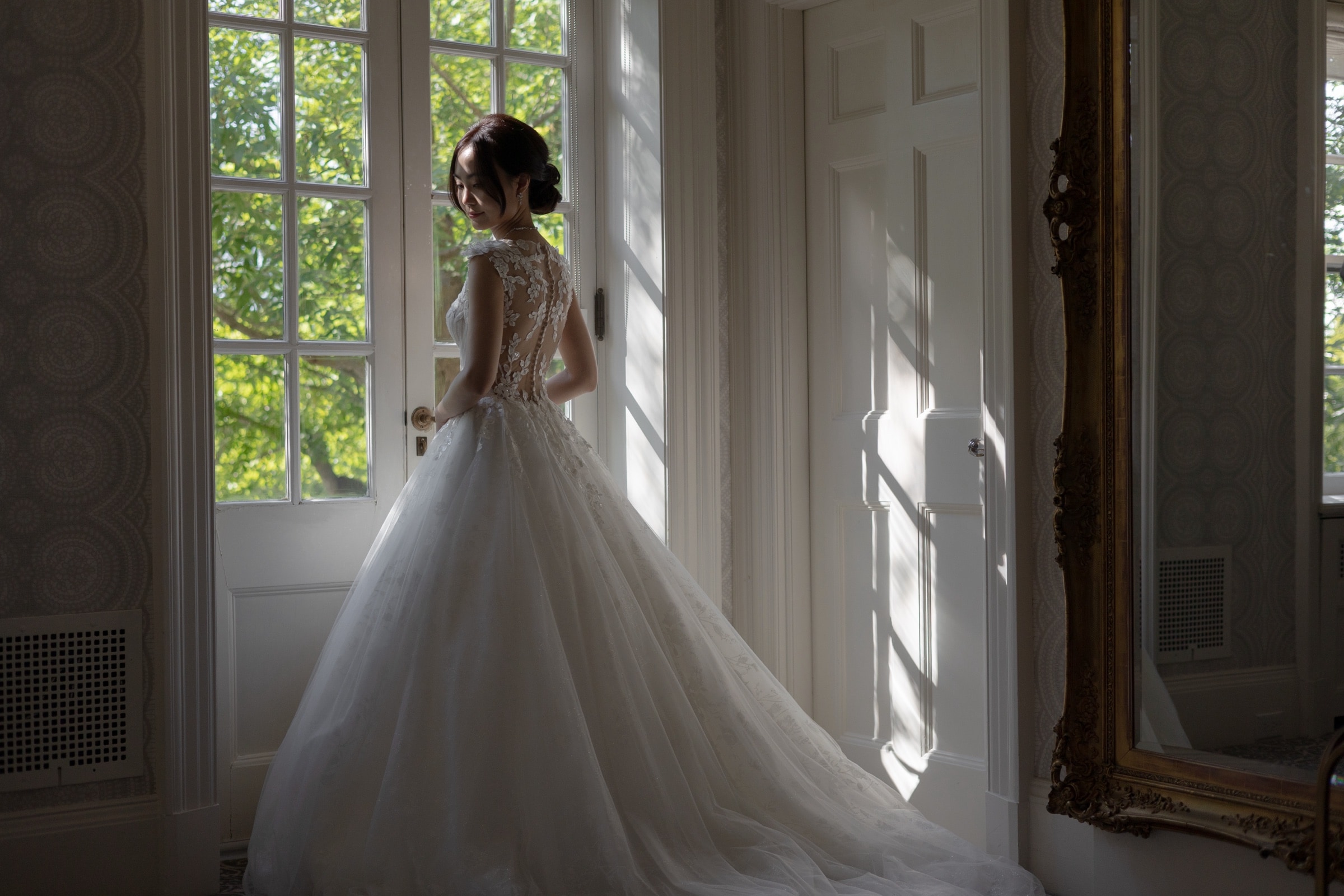 The back of the bride's beaded gown in window light