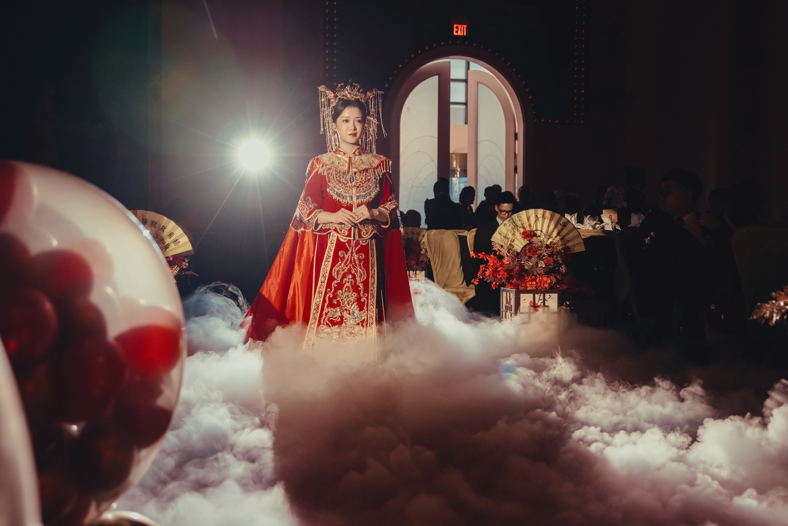 Traditional Chinese wedding entrance — the bride in a 秀禾 gown amid stage fog