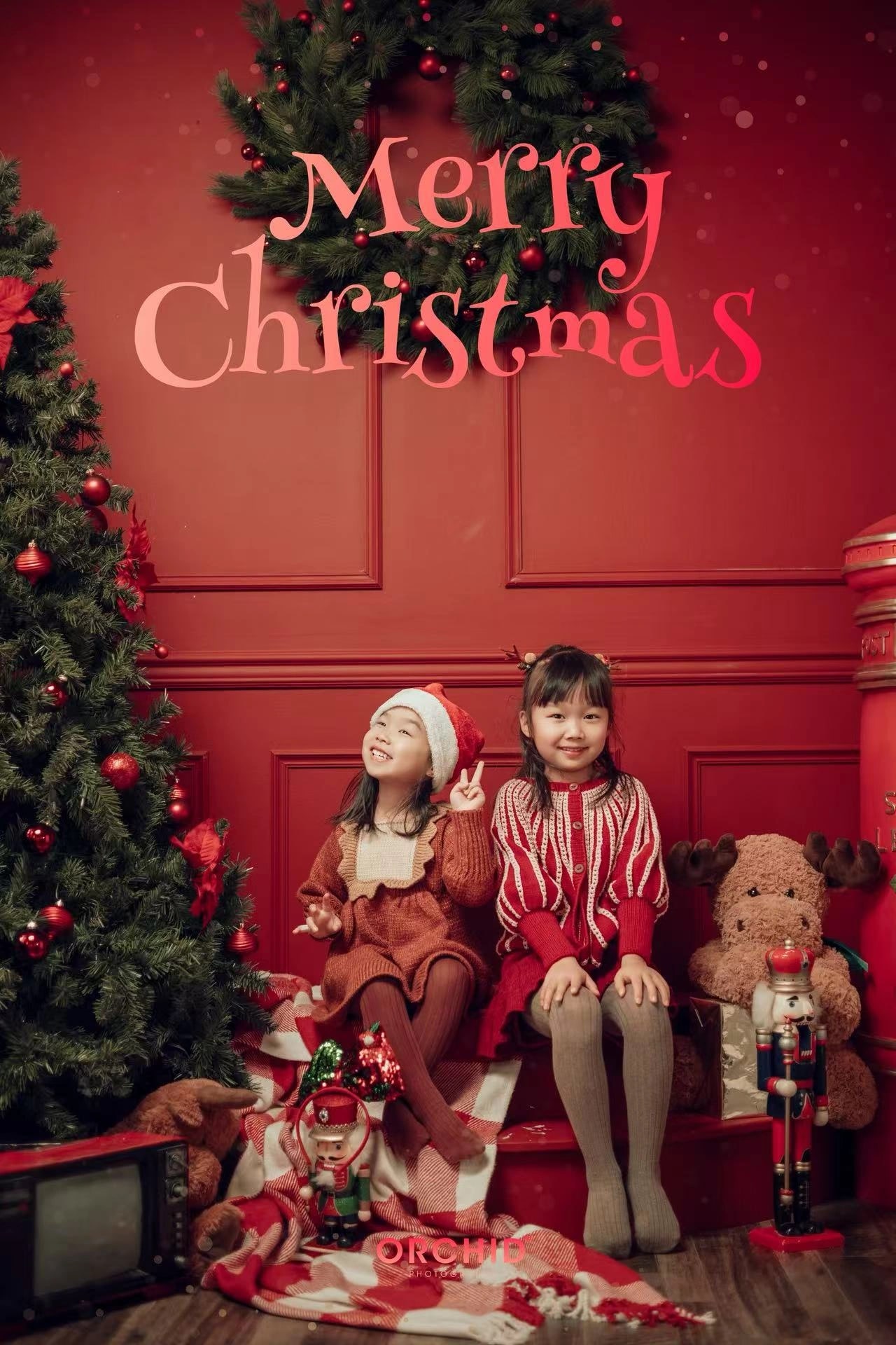 Christmas Wonder — two sisters by the red wall